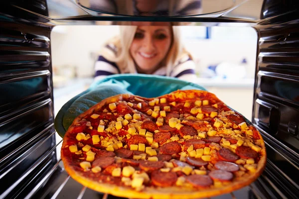 Kvinna att sätta Pizza i ugnen — Stockfoto