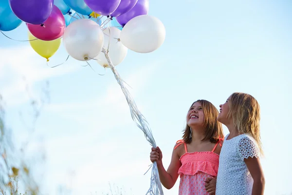 Unga tjejer hålla ballonger — Stockfoto