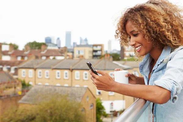 Vrouw met behulp van mobiele telefoon op dak — Stockfoto