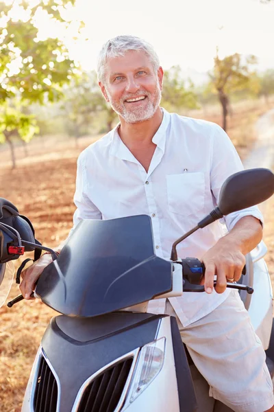Человек зрелого возраста ездит на мотороллере — стоковое фото