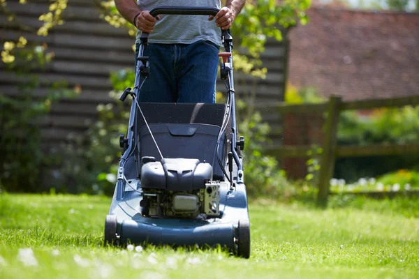 Homem trabalhando no jardim cortando grama — Fotografia de Stock