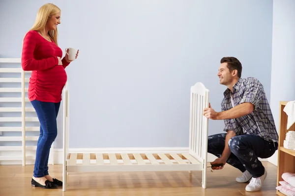 Couple Assembling Cot In Nursery — Stock Photo, Image