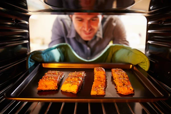 Hombre poniendo salmón en el horno — Foto de Stock