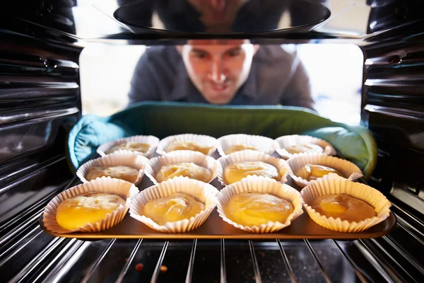 Homem colocando cupcakes no forno — Fotografia de Stock