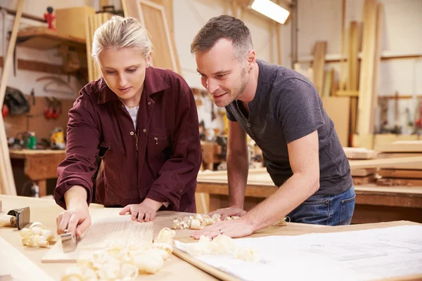 Falegname con apprendista donna piallatura di legno — Foto Stock