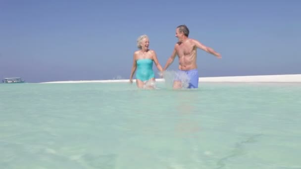 Senior couple running through sea towards — Stock Video