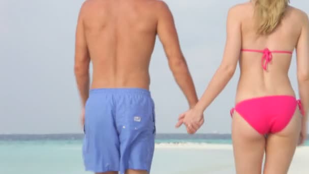 Paar lopen langs camera en langs strand. — Stockvideo