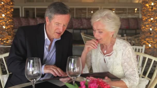 Seniorenpaar schaut sich Speisekarten im Restaurant an — Stockvideo