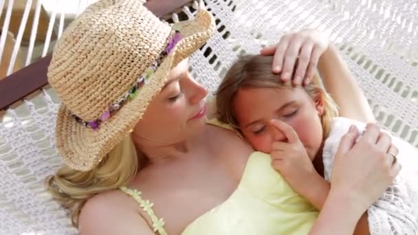 Mother cuddling daughter as they swing in hammock. — Stock Video