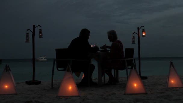 Senior paar genieten van de avondmaaltijd op strand — Stockvideo