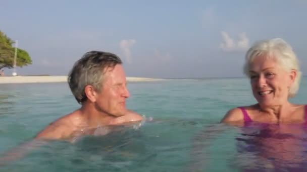 Старшая пара болтать и плавать на спинах — стоковое видео