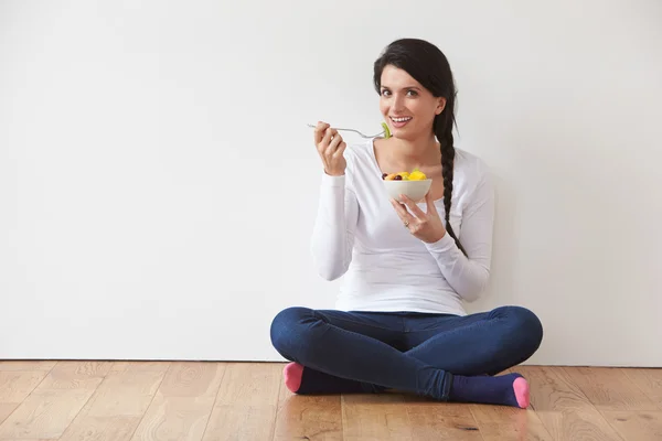 Mulher sentada no chão comendo frutas — Fotografia de Stock