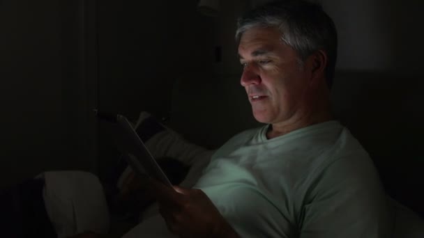 Man met tablet pc in bed — Stockvideo