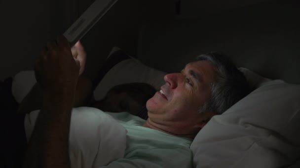 Man met tablet pc in bed — Stockvideo