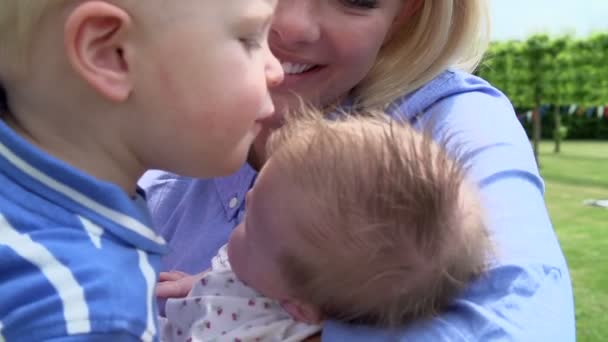 少年は、生まれたばかりの妹の庭のキスを与えるchlapec dává novorozence mladší sestra polibek — Stock video