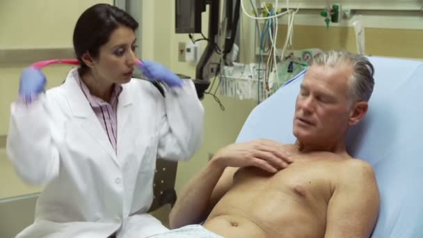 Лікар оглядає пацієнта в лікарняному ліжку — стокове відео