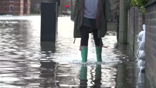Женщина, идущая по затопленной улице — стоковое видео