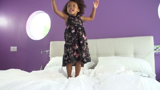 Милая маленькая девочка прыгает на кровати родителя — стоковое видео