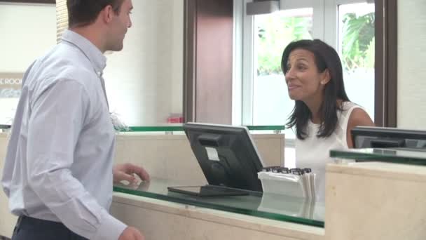 Hombre registrándose en la recepción del hotel usando tableta digital — Vídeo de stock