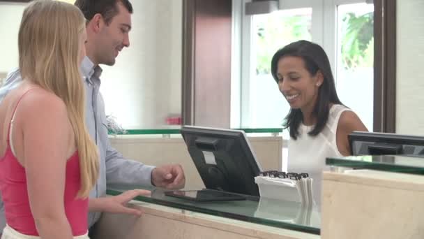 Pareja registrándose en la recepción del hotel usando tableta digital — Vídeo de stock