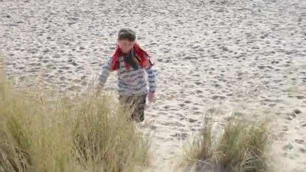 Ung pojke löper genom sanddyner — Stockvideo