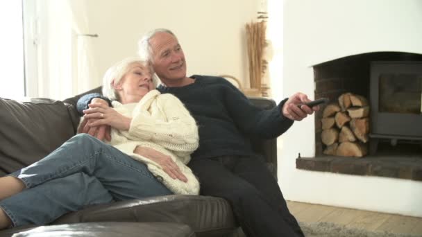 Pareja mayor sentada en un sofá viendo televisión — Vídeos de Stock