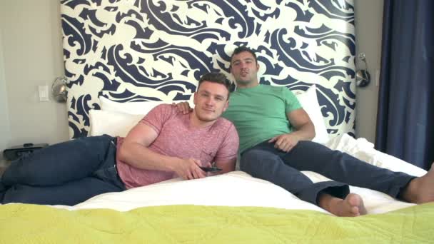 Мужская пара отдыхает в гостиничном номере, смотрит телевизор — стоковое видео