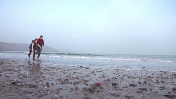 Padre e hijo corriendo en la playa de invierno — Vídeo de stock