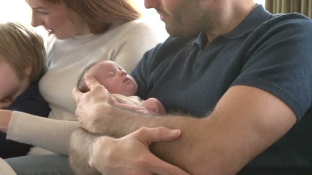 Familia sentada en sofá con bebé recién nacido — Vídeo de stock