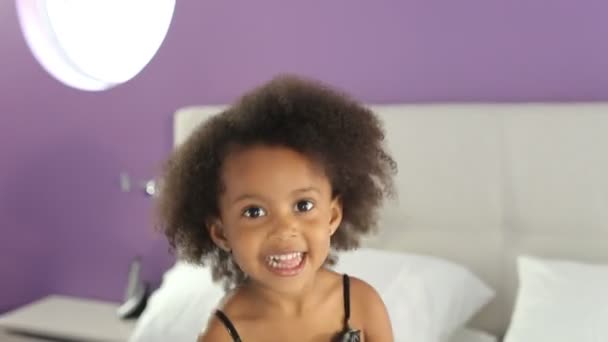 Aranyos kislány ugrál a szülők ágyán. — Stock videók