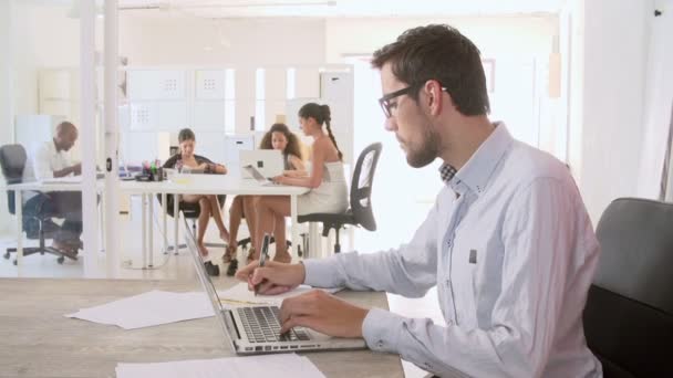Hombre usando el ordenador portátil y tomando notas — Vídeo de stock
