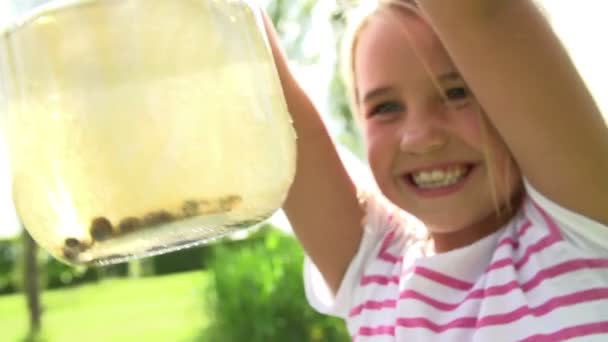 Mädchen hält Glas mit Kaulquappen — Stockvideo