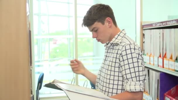 Masculino-estudante procurando informações na biblioteca — Vídeo de Stock