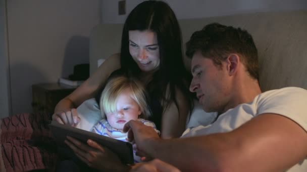 Familie sitzt im Bett und schaut auf digitales Tablet — Stockvideo