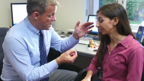 Médico que ajusta o paciente feminino com aparelho auditivo — Vídeo de Stock