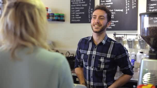 Hombre sirviendo a cliente femenino en la cafetería — Vídeos de Stock