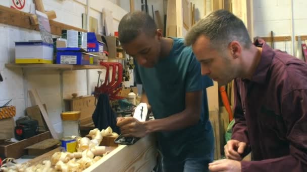 Timmerman met leerling schaven van hout In Workshop — Stockvideo