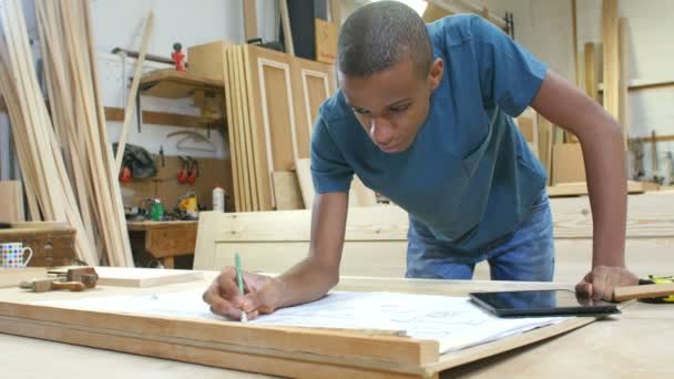 Carpintero con aprendiz mirando los planes en el taller — Vídeos de Stock