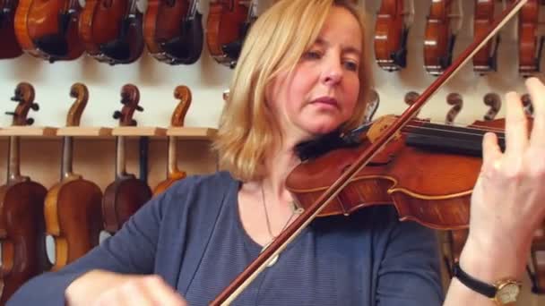 客户尝试小提琴在音乐商店 — 图库视频影像