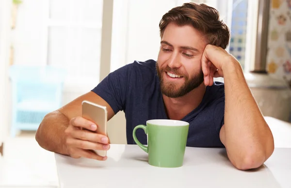 Uomo che utilizza il telefono cellulare a casa — Foto Stock