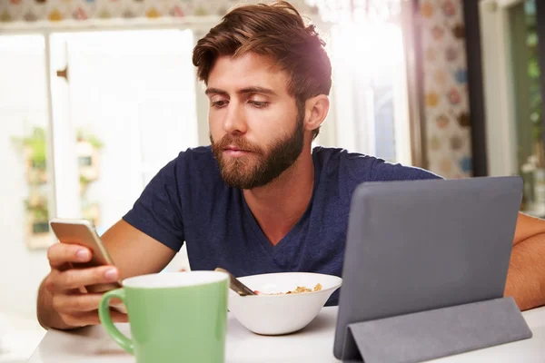 Homem comendo café da manhã com telefone — Fotografia de Stock
