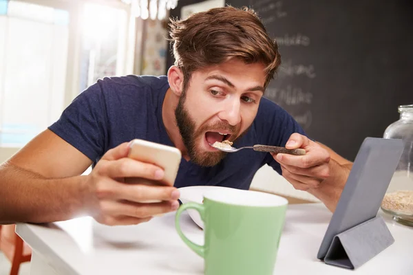 Hombre comiendo desayuno con teléfono — Foto de Stock