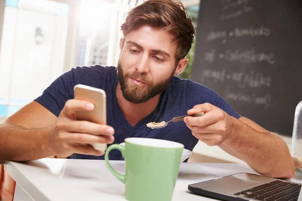 Homem comendo café da manhã com dispositivos — Fotografia de Stock