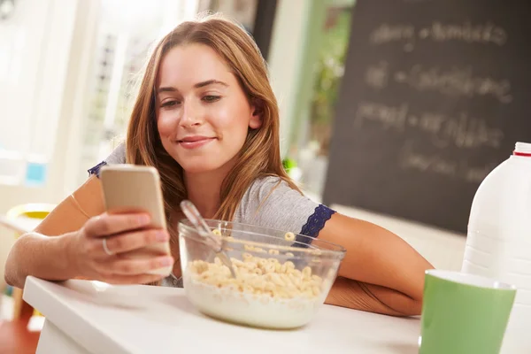 Женщина во время завтрака с помощью мобильного телефона — стоковое фото