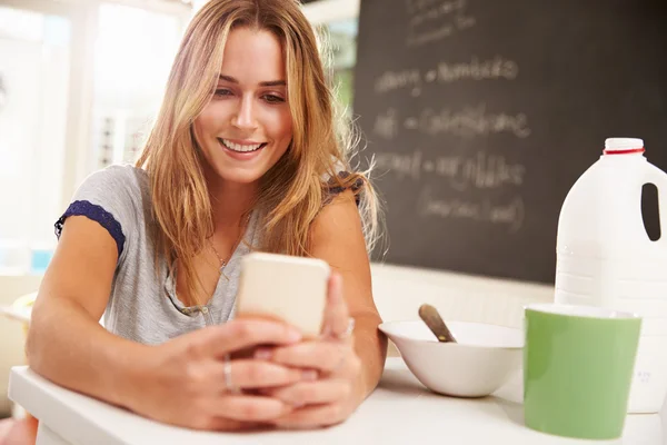 Mulher durante o café da manhã usando telefone móvel — Fotografia de Stock