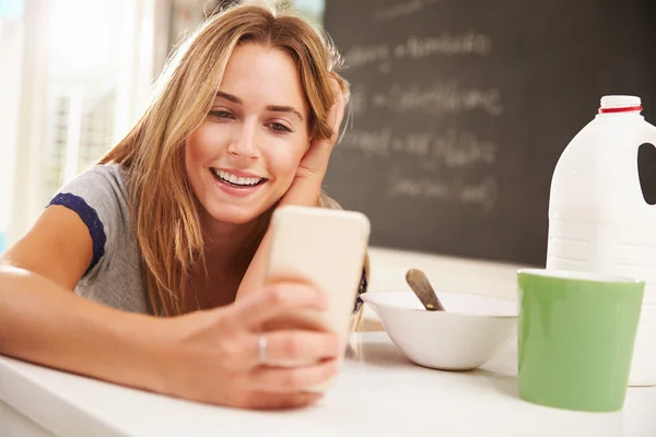 Женщина во время завтрака с помощью мобильного телефона — стоковое фото