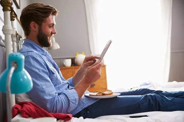 Mann frühstückt im Bett mit digitalem Tablet — Stockfoto