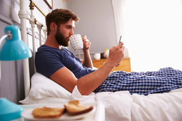 Homem comendo café da manhã na cama — Fotografia de Stock