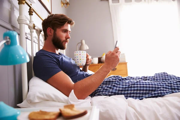 Человек ест завтрак в постели — стоковое фото