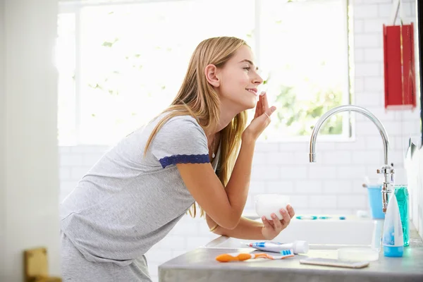 Mujer poniéndose crema hidratante en el baño —  Fotos de Stock